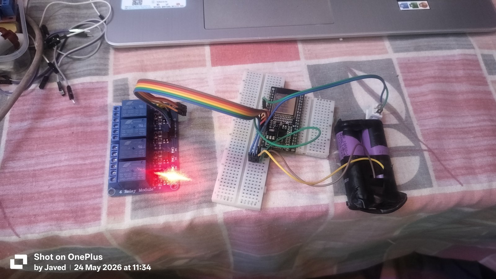 Figure 6: Top-down hardware bench setup showing the ESP32 microcontroller, decoupled battery power pack, and 4-channel relay module.