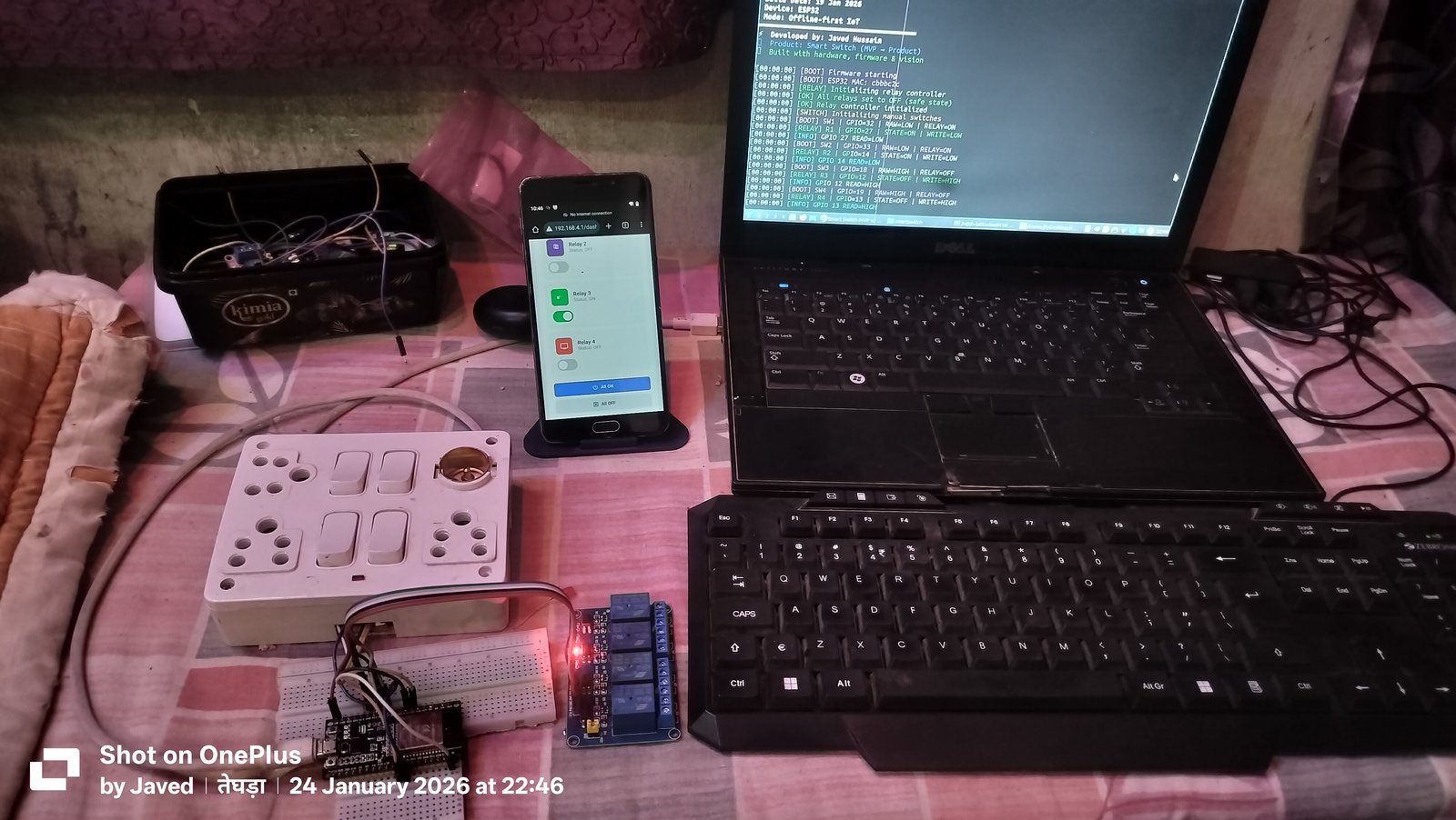 Figure 3: The complete Smart Switch system: Laptop running PlatformIO serial telemetry, smartphone hosting the local captive portal at 192.168.4.1/dash, physical switchboard, and active 4-channel relay module.